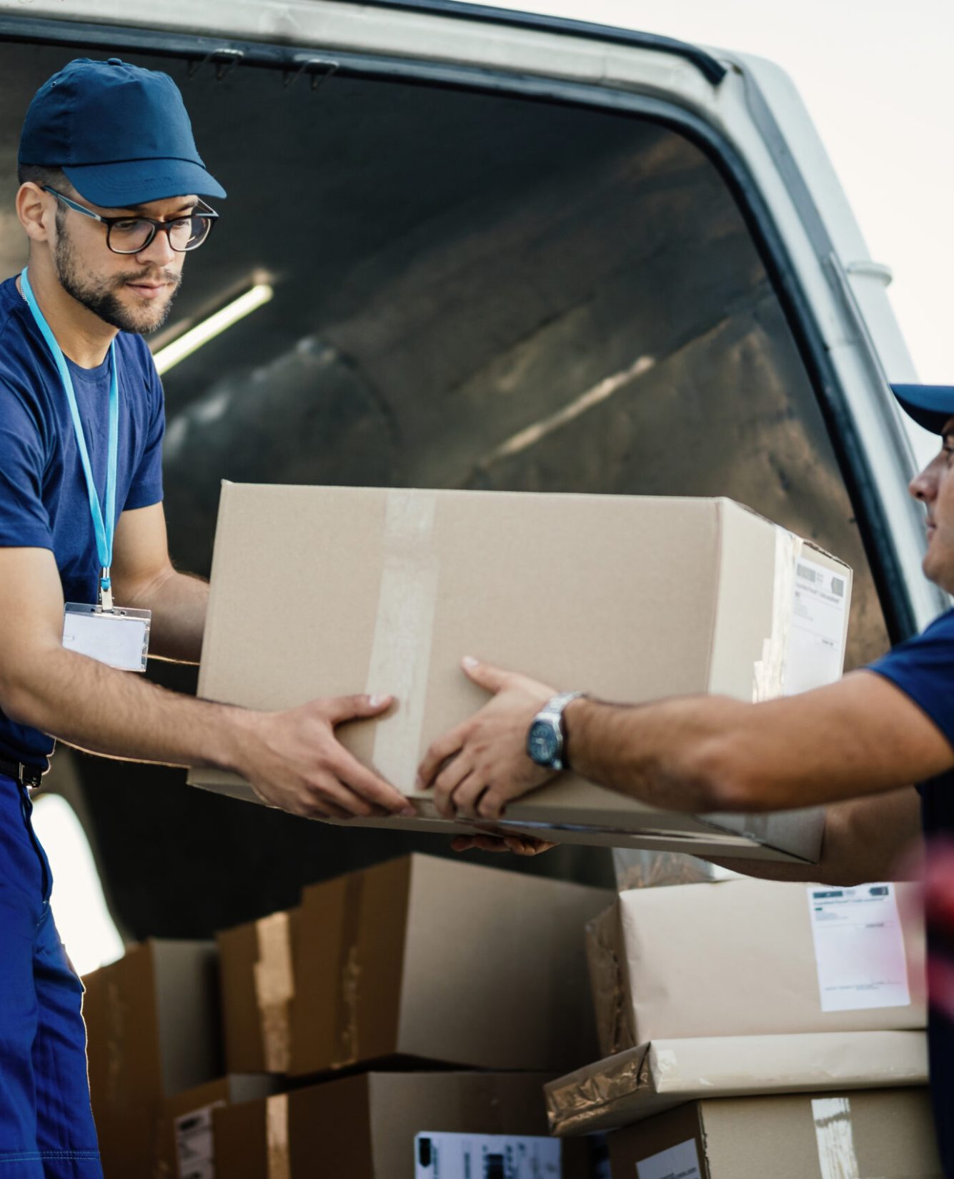 Delivery men loading carboard boxes in a van while getting ready for the shipment.